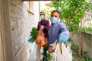 two men handing over groceries